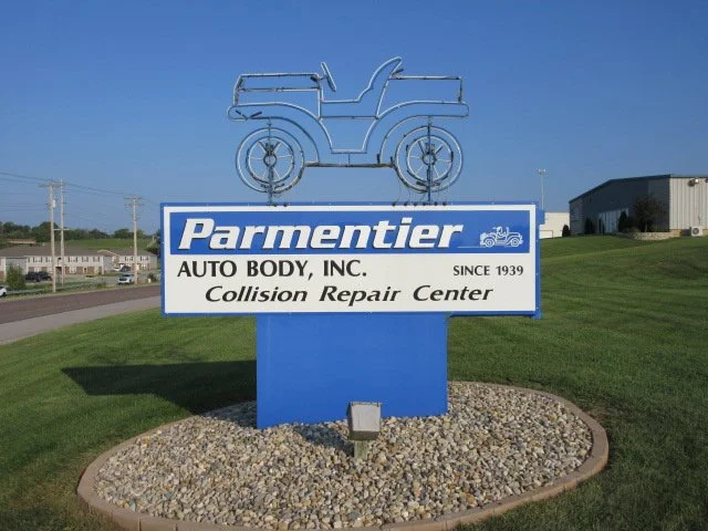 Sign for Parmentier Auto Body, Inc. Collision Repair Center with a neon outline of an old-fashioned truck on top.