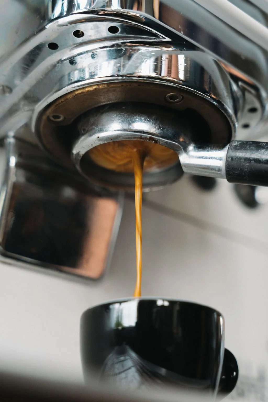 Close-up of a coffee machine pouring coffee into a black mug.