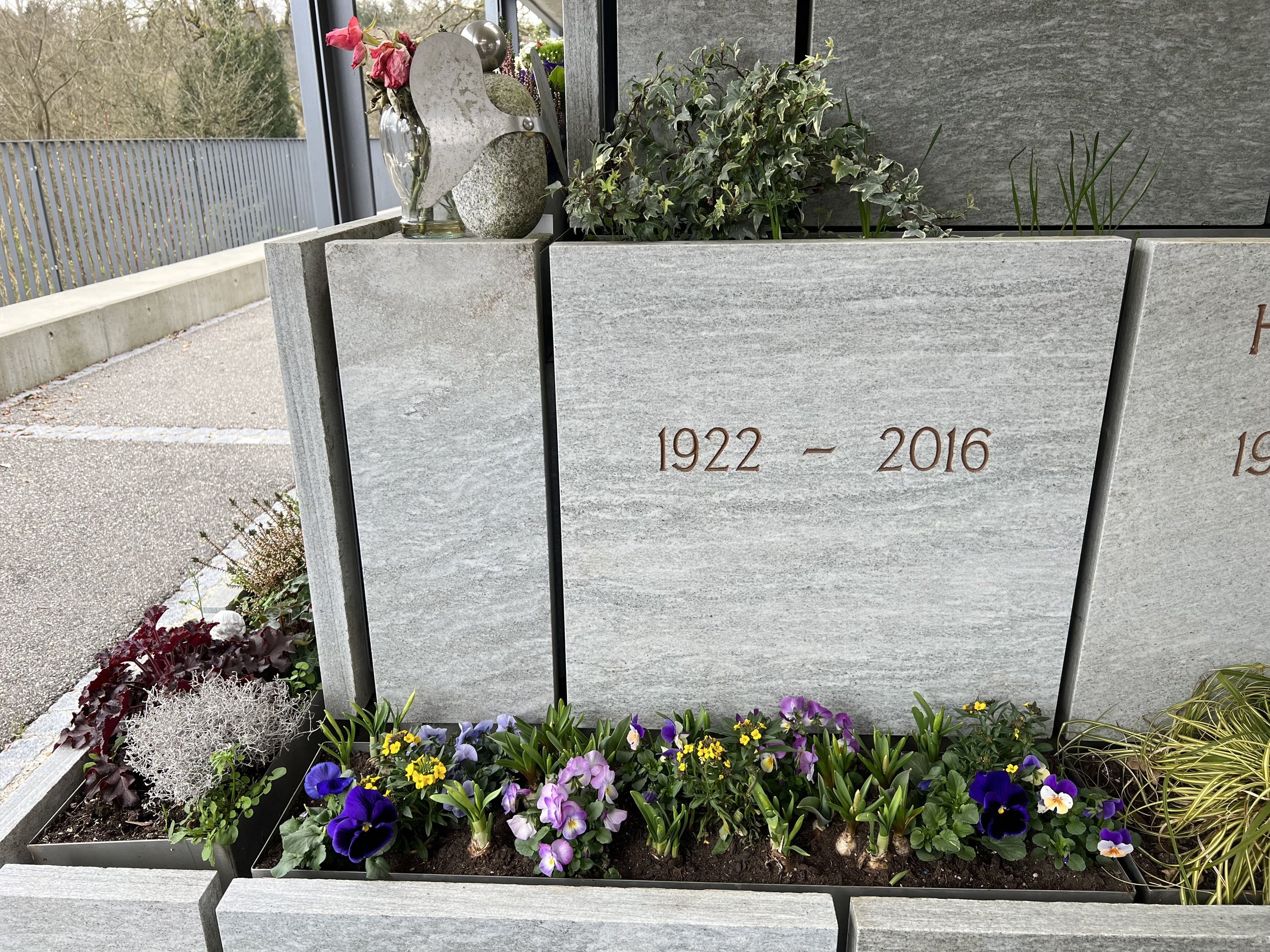 Blumen und eine Gedenktafel mit den Jahren 1922 und 2016.