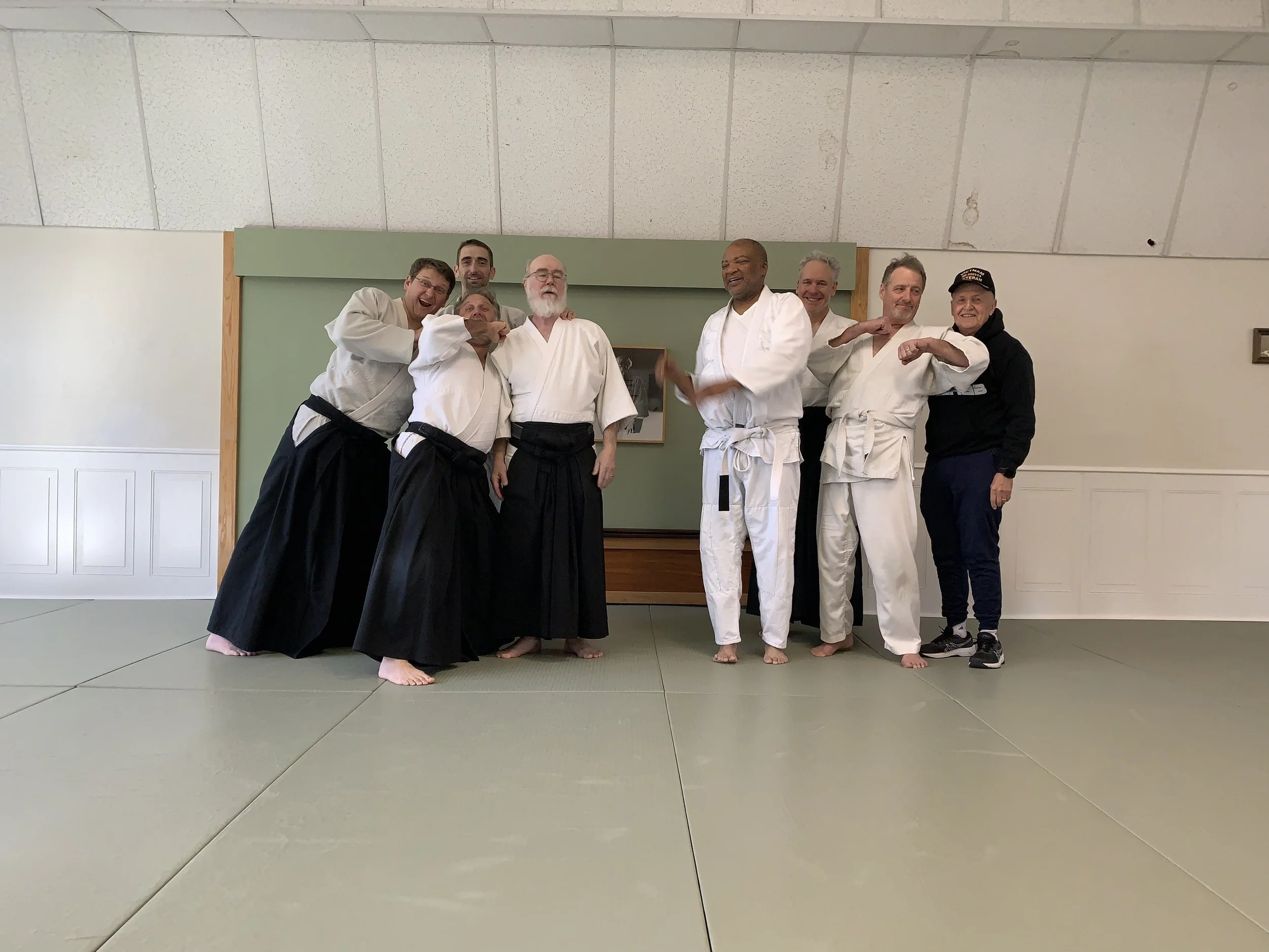Group of seven students posing for a group photo at Aikido of Norfolk in Virginia, including Shihan James Baker in the center.