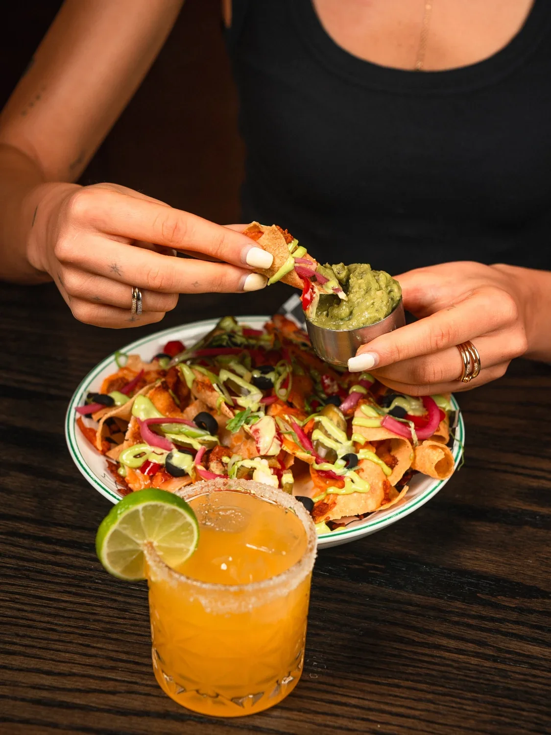 A lime-garnished cocktail beside nachos at The Fortunate Fox