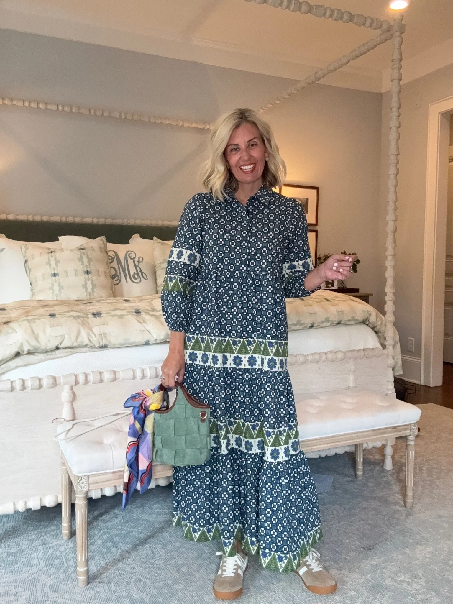 A woman with blonde hair smiling and standing in a living room.