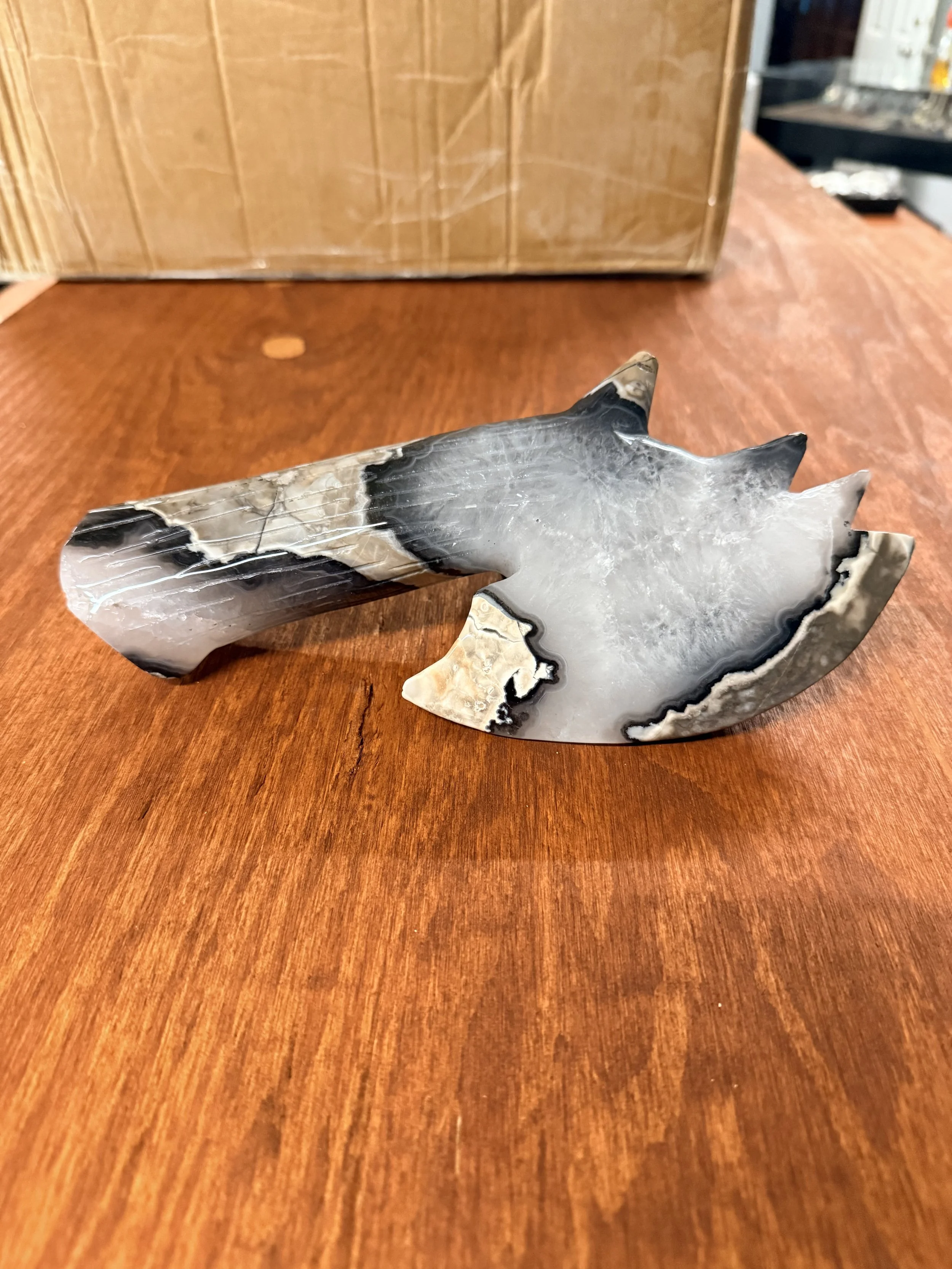A piece of polished black and white marble with a complex pattern, resting on a wooden surface.