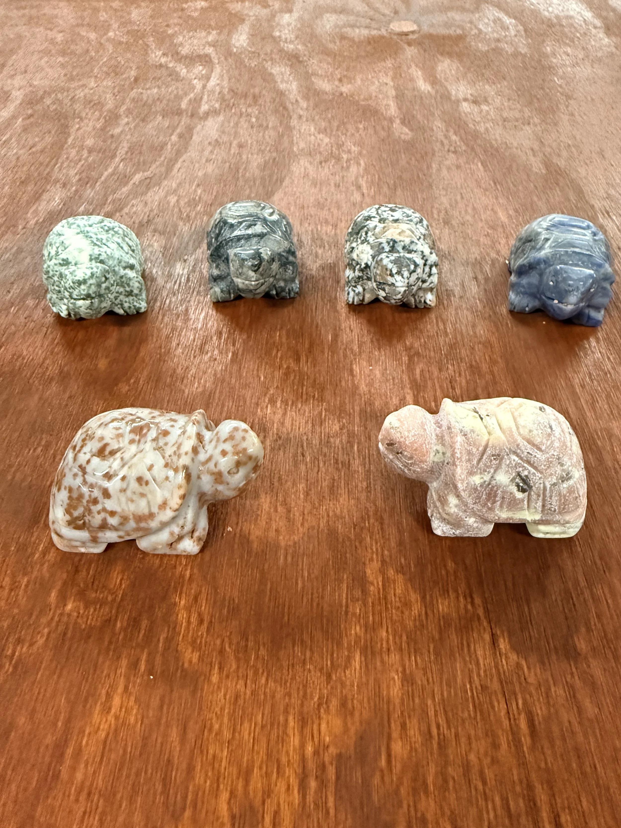 Four carved stone elephant figurines on a wooden surface.