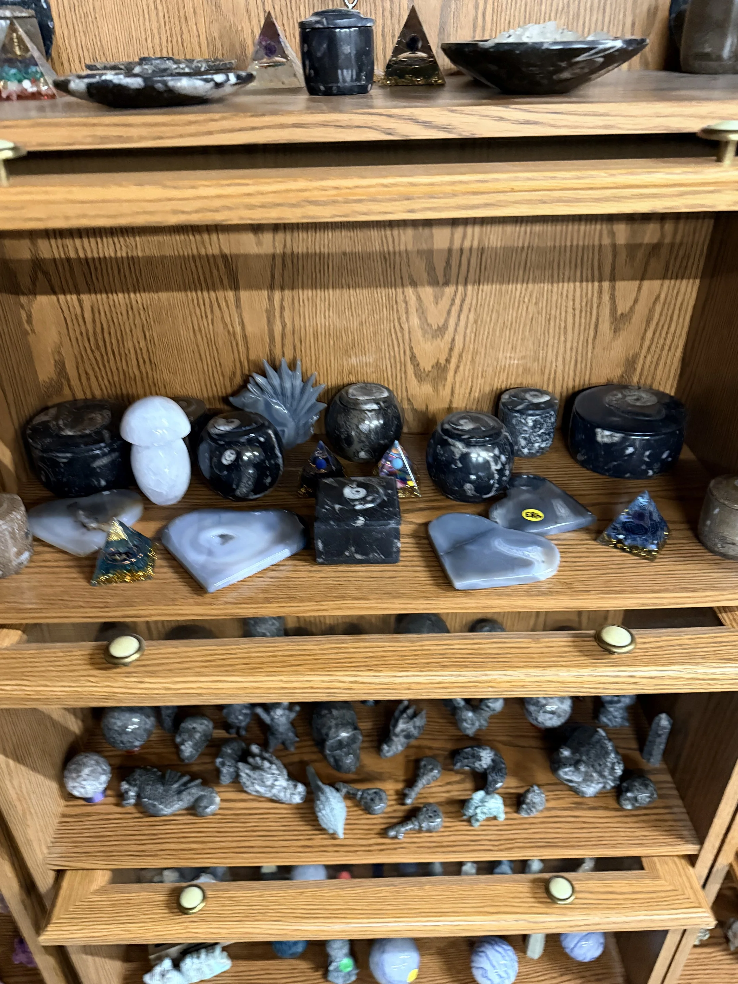 Wooden shelves displaying various rocks and minerals, including polished stones, agates, and geodes.