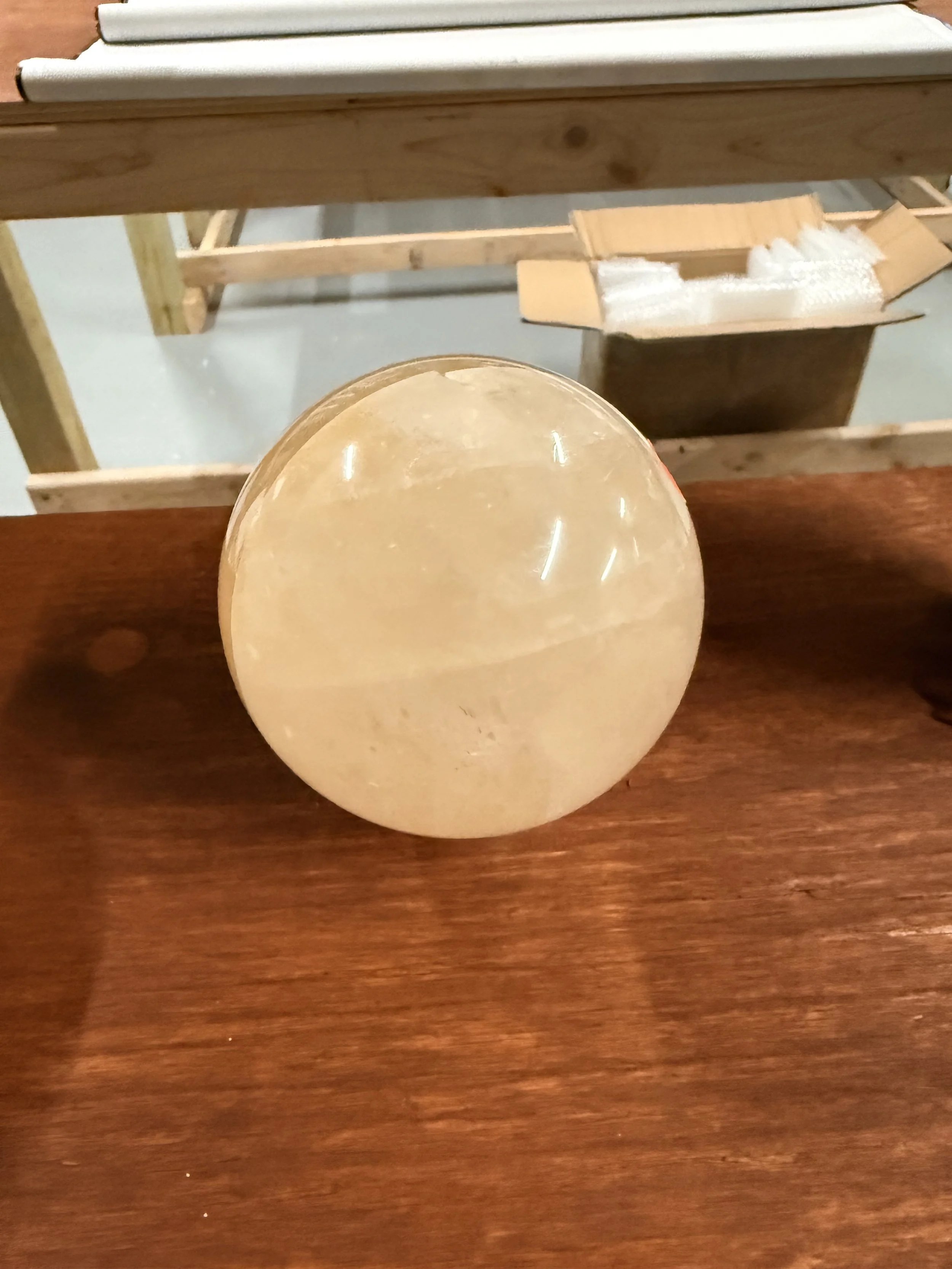 A large, round, yellowish-orange orb or sphere on a wooden surface.