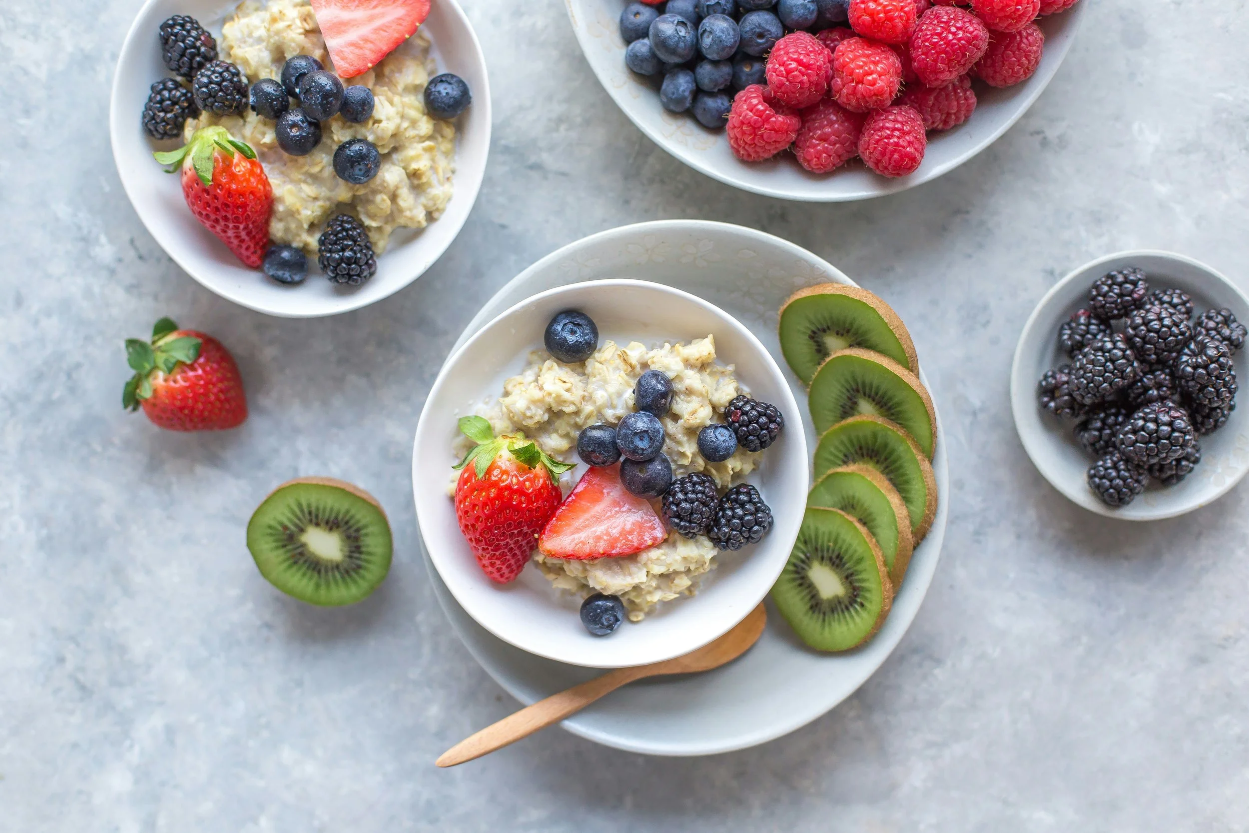 fiber Bowls of oatmeal topped with berries and sliced fruit.