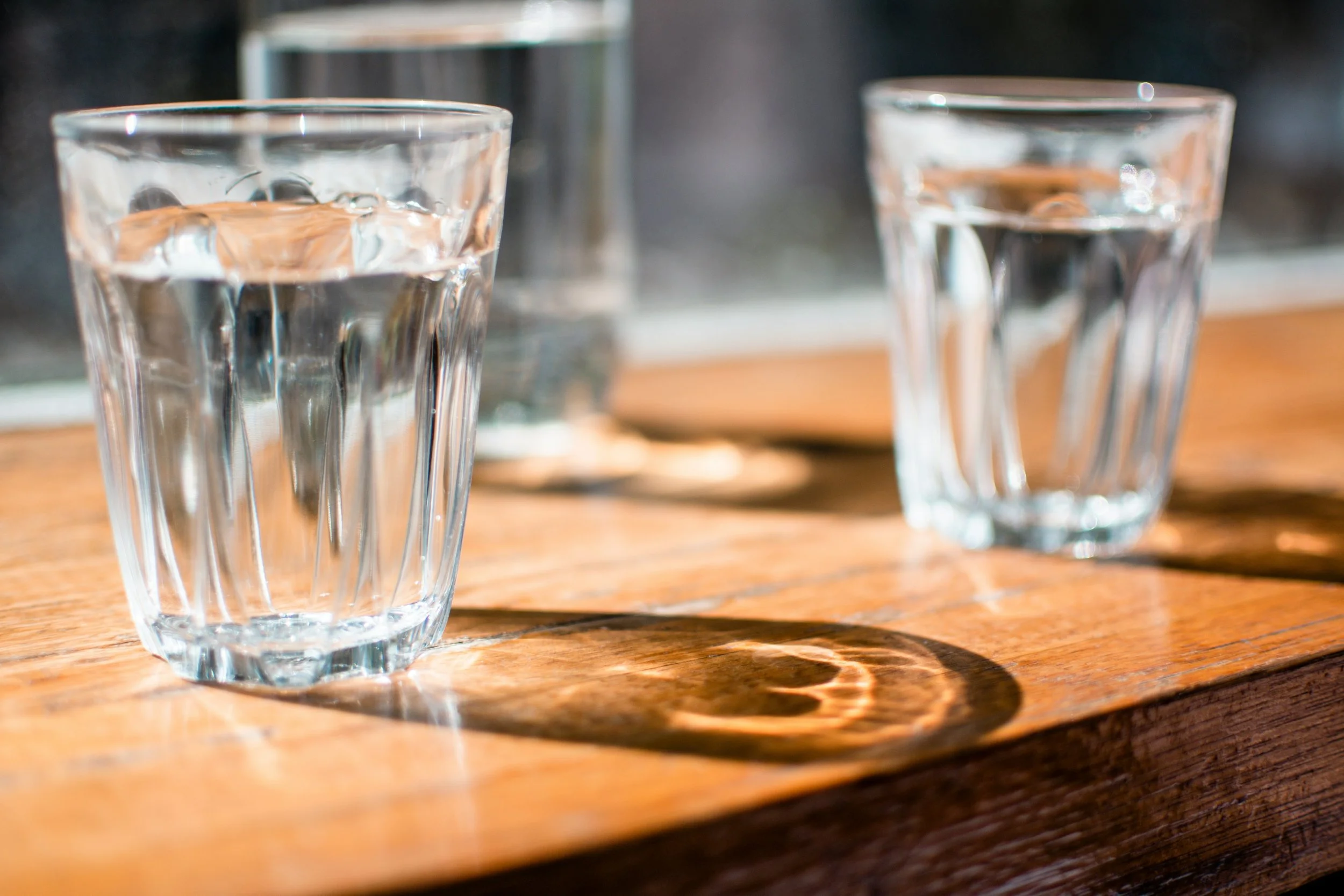 Hydration Two glasses of water on a wooden surface in sunlight.