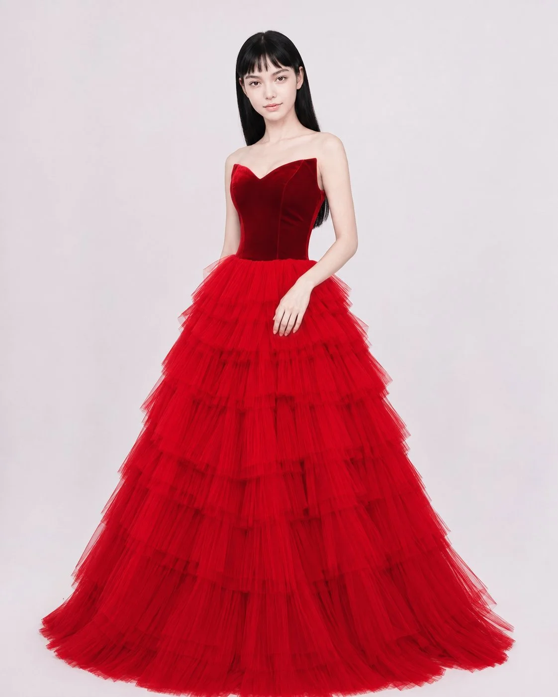 A woman wearing a strapless red ball gown with a ruffled tulle skirt and fitted velvet bodice.