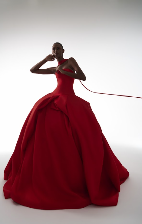 A woman in a striking red ball gown with a full skirt and fitted bodice, posing against a plain background.