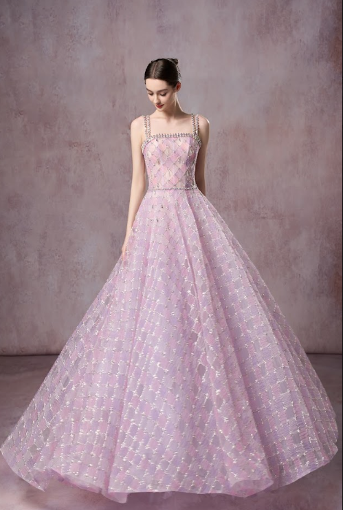 A young woman in a pink and purple checkered ball gown with spaghetti straps, standing against a plain background.