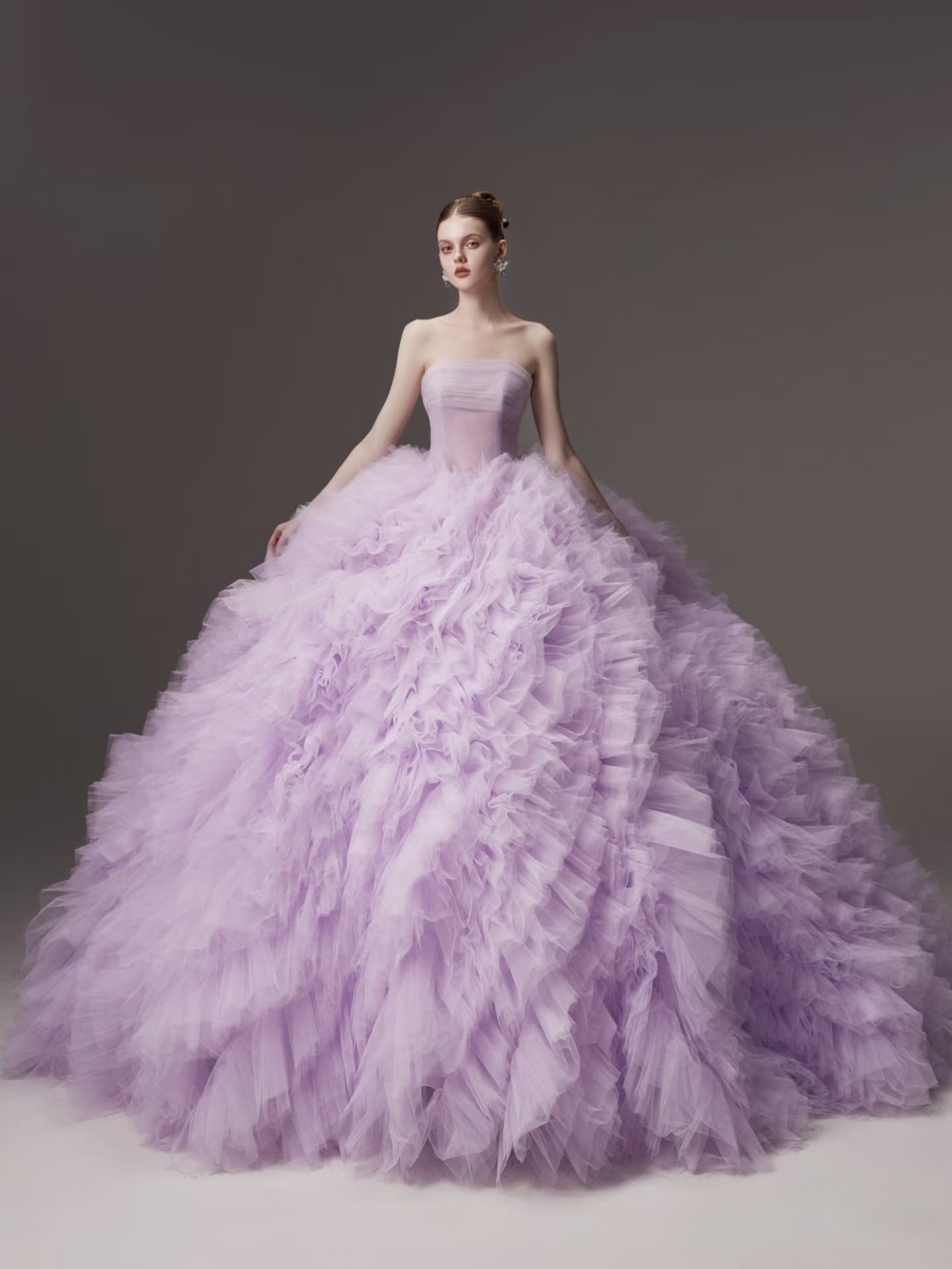 A woman in a strapless, lavender ball gown with a full, ruffled tulle skirt.