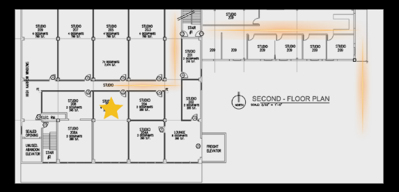 Second-floor architectural blueprint of a building with designated studio rooms, a lounge, an elevator, and staircases, along with a yellow star marking a specific location.