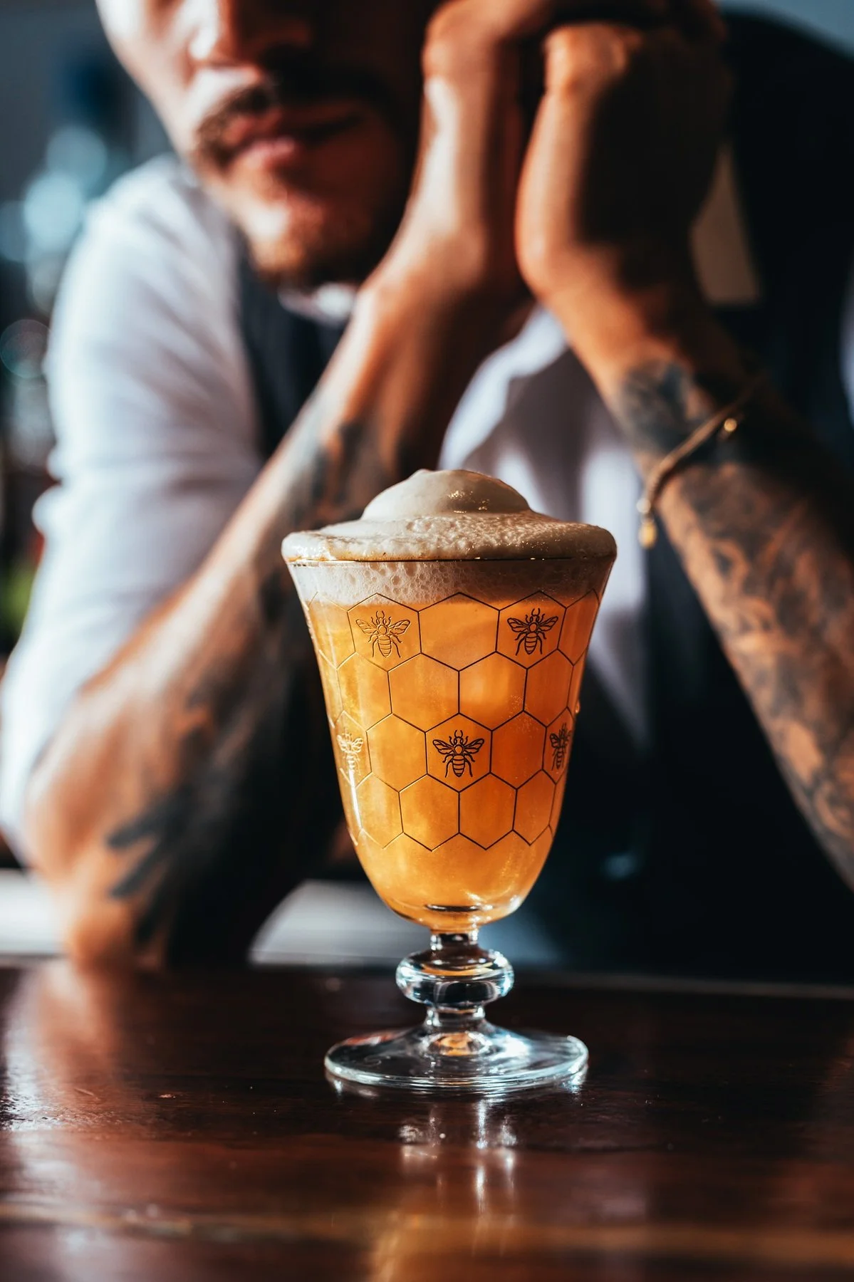 Close-up of a beer glass with honeycomb and bee artwork at the Hinoki Burlington bar.