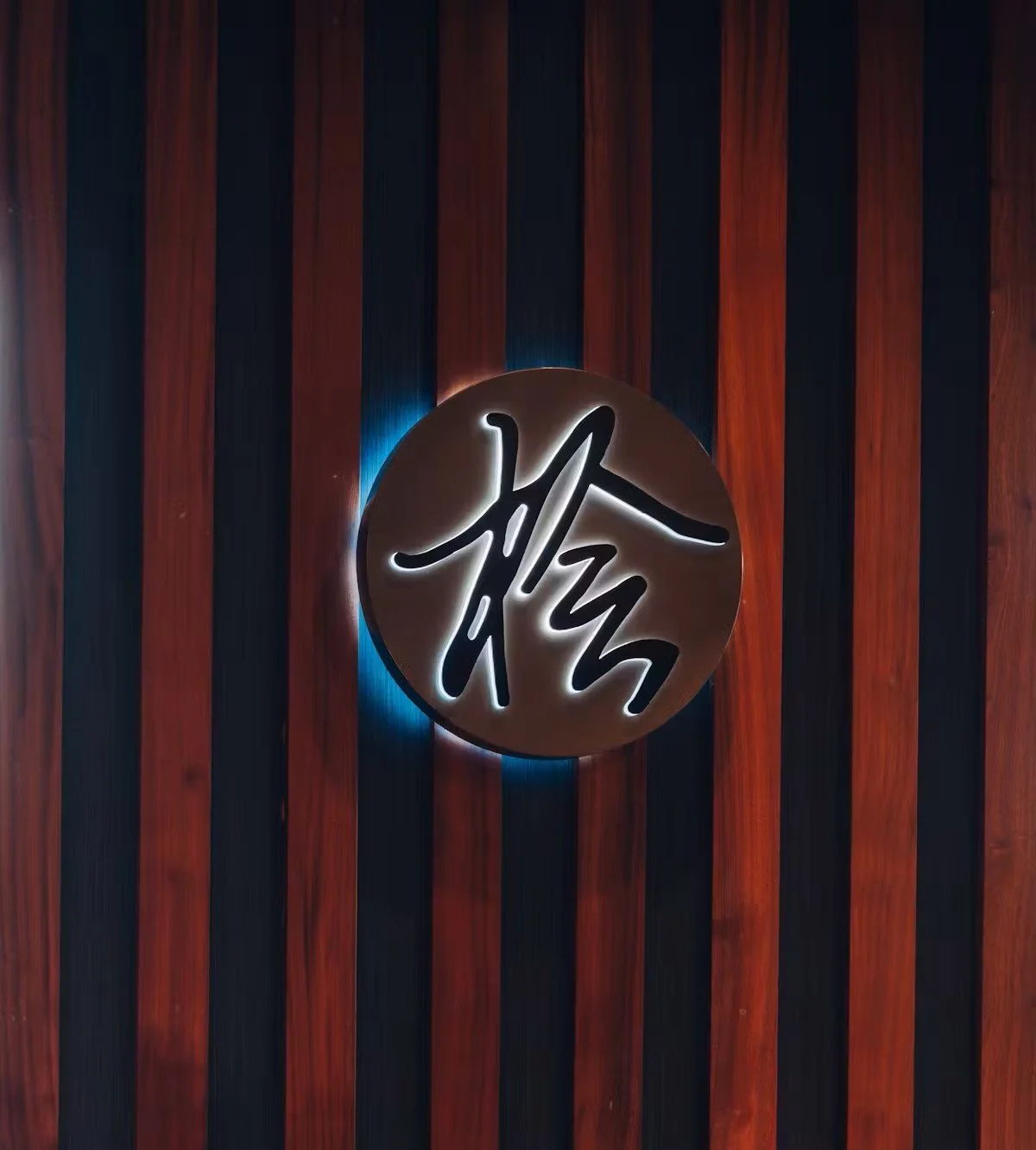 Illuminated Hinoki Burlington Japanese sign mounted on a dark wood-paneled wall.