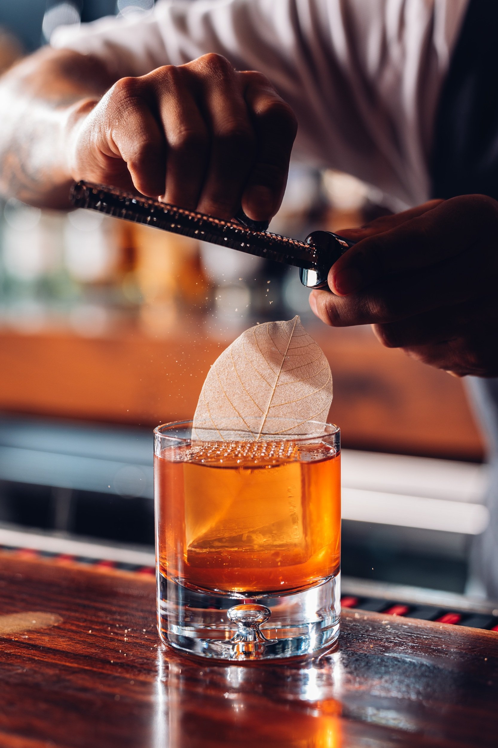 Bartender zesting fresh orange over a handcrafted cocktail at Hinoki Burlington Japanese restaurant.