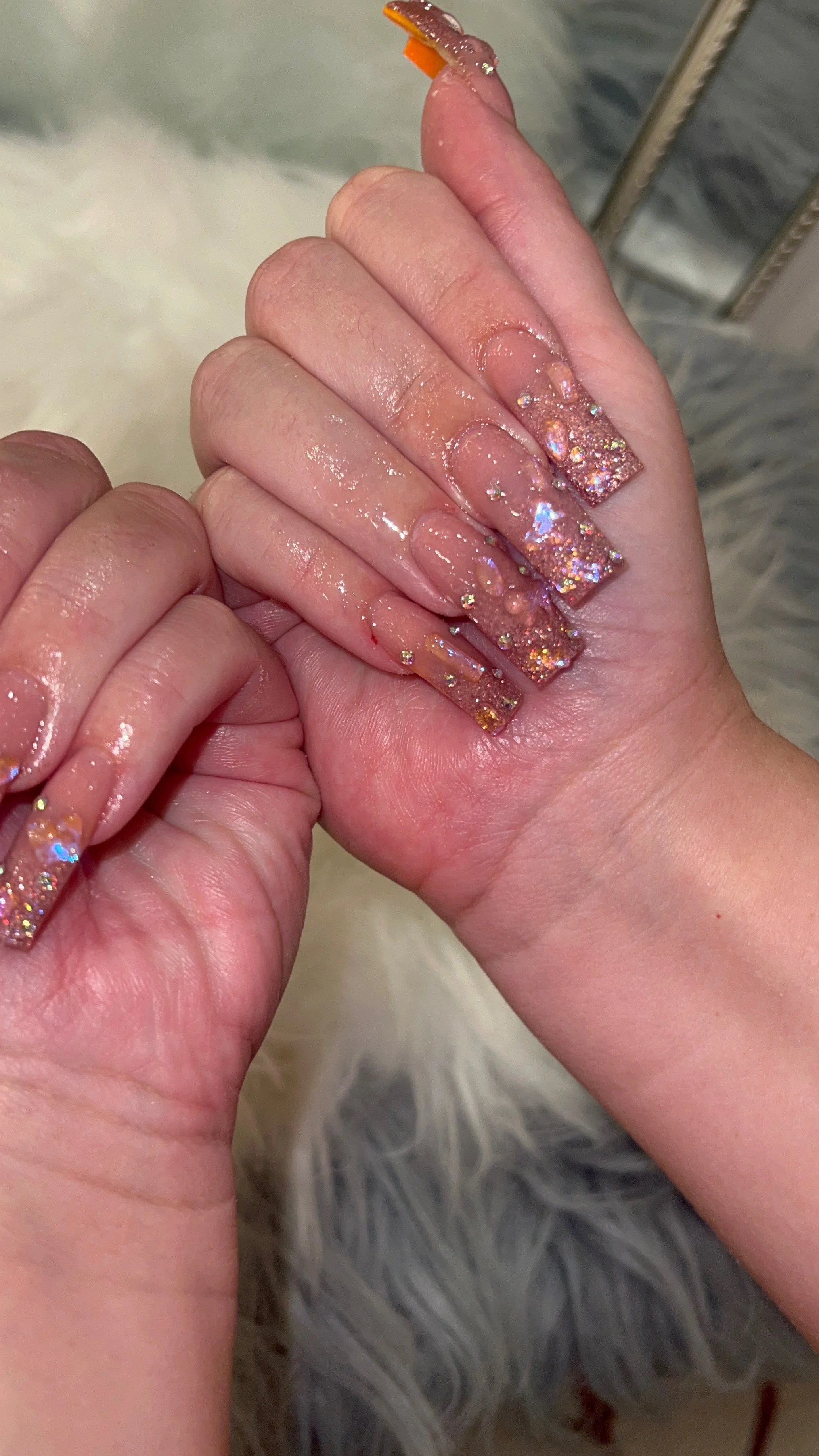 Rose-gold glitter acrylic nails with sparkling crystal details.