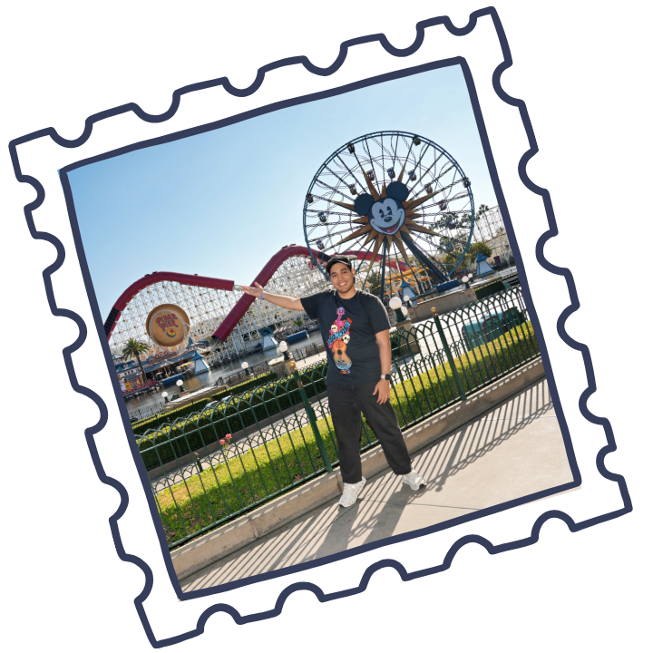 Person standing in front of a Disney theme park attraction featuring a large Mickey Mouse Ferris wheel and a roller coaster.