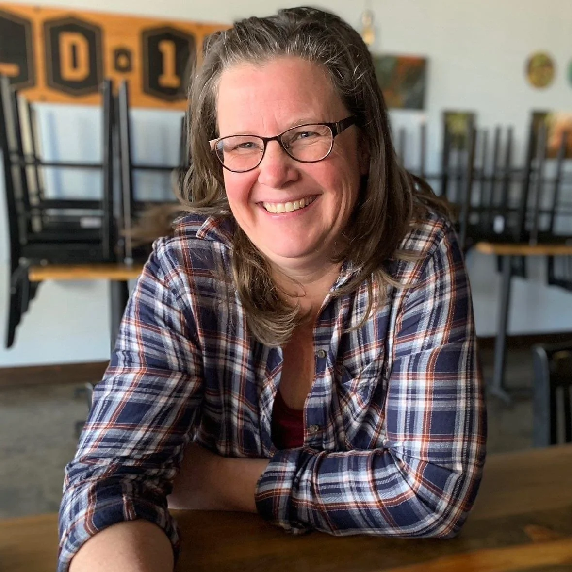 Wendy, the teacher behind Carve by Numbers, smiling at a wooden table