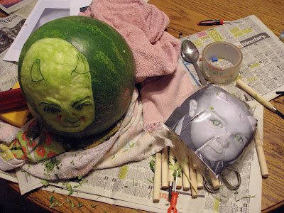 The watermelon partway through carving, with tools and the reference photo beside it