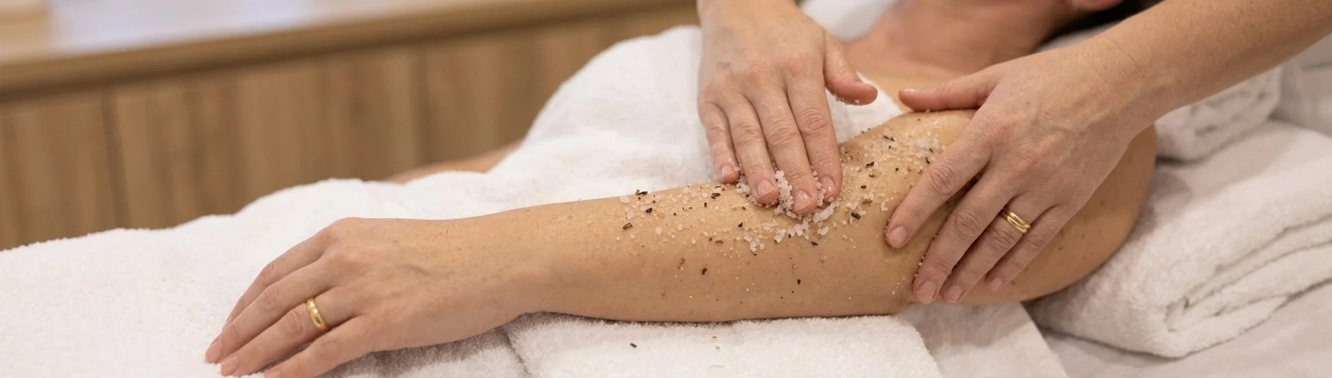 Person receiving a salt scrub massage on their forearm in a spa setting.