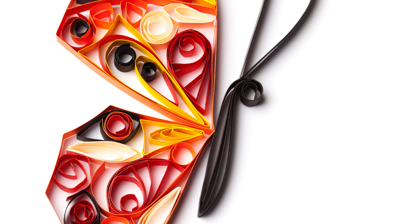 Colorful paper quilling butterfly with orange, yellow, red, black, and cream paper strips and delicate curled shapes.