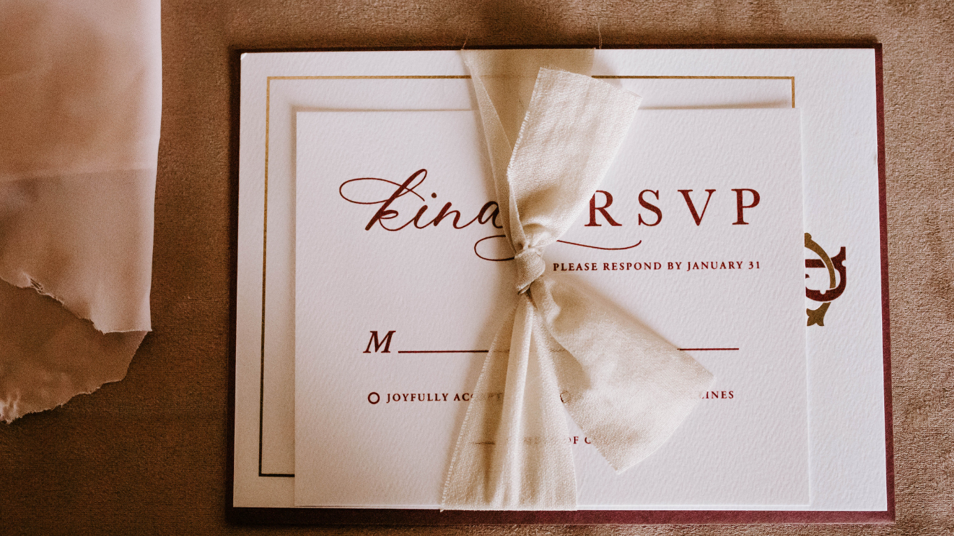 A wedding RSVP card tied with a fabric ribbon on a table.