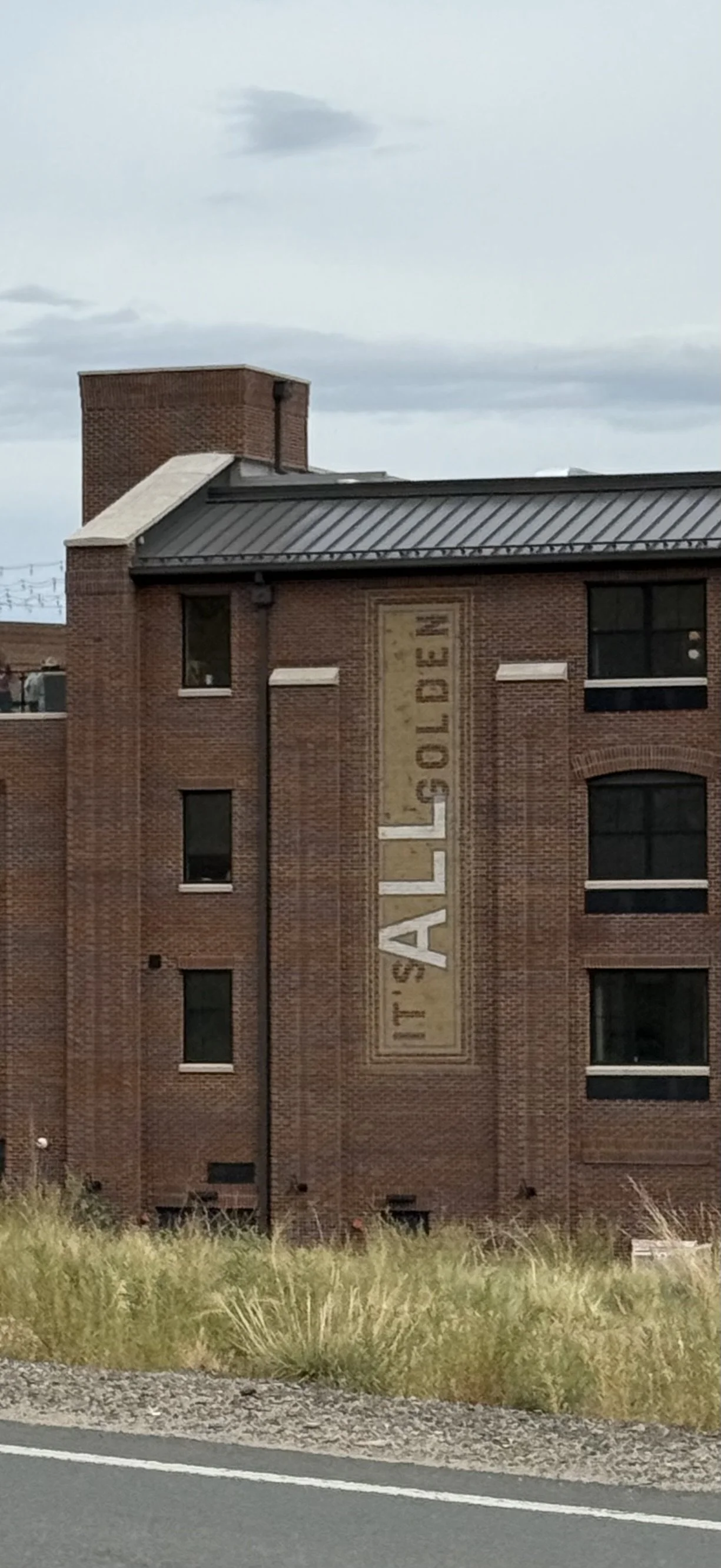 A brick building with a vertical sign that reads 'IT'S ALL GOLDEN.'
