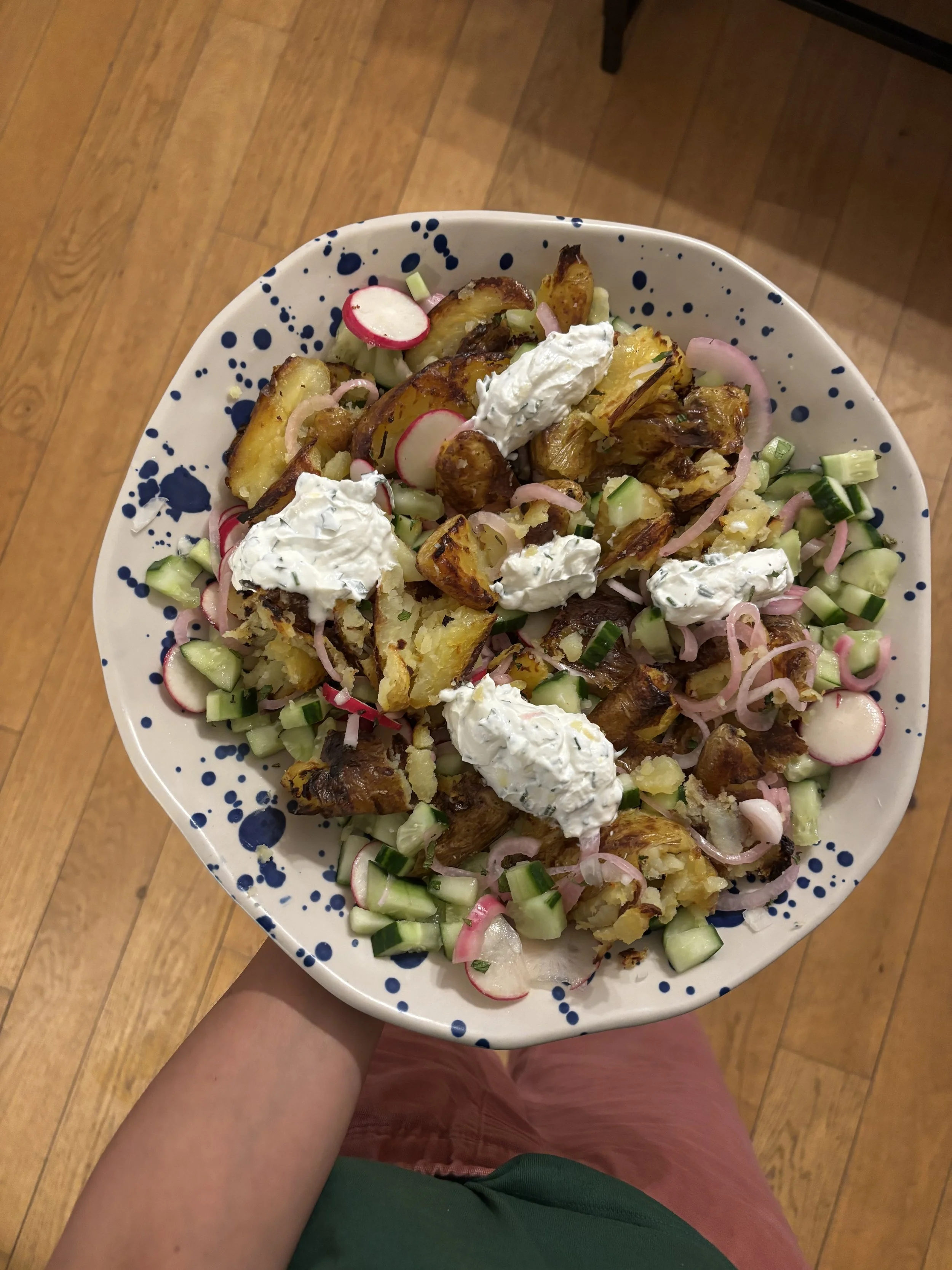 Assiette de pommes de terre, radis, oignons et crème, vue du dessus, dans une main d'enfant, avec un sol en bois au fond.