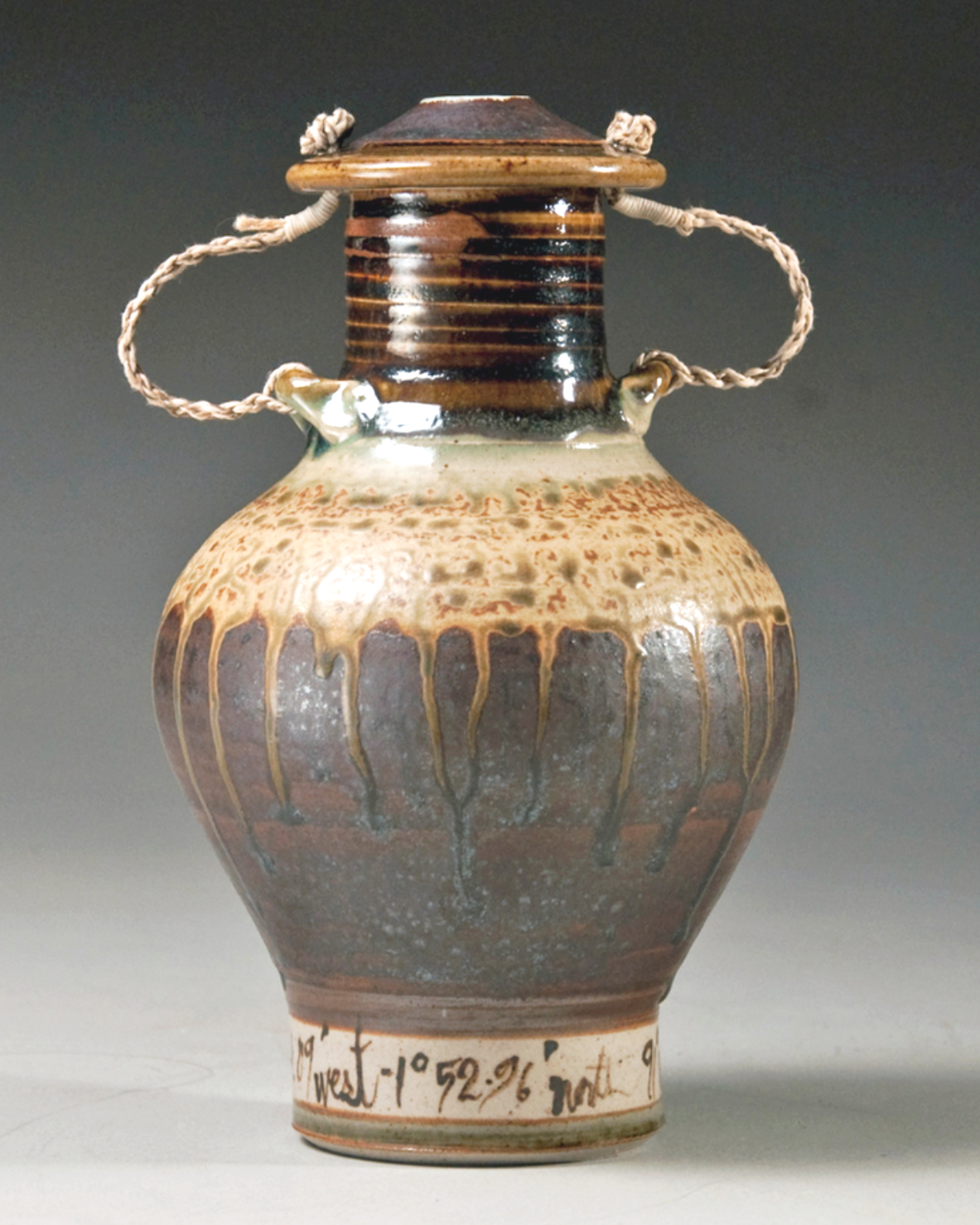 A ceramic urn glazed with two Galapagos seafloor sediments. Twisted twine loops attach lid to jar.  handles, Rounded body highlights branching patterns in shades of brown, beige, and gray.