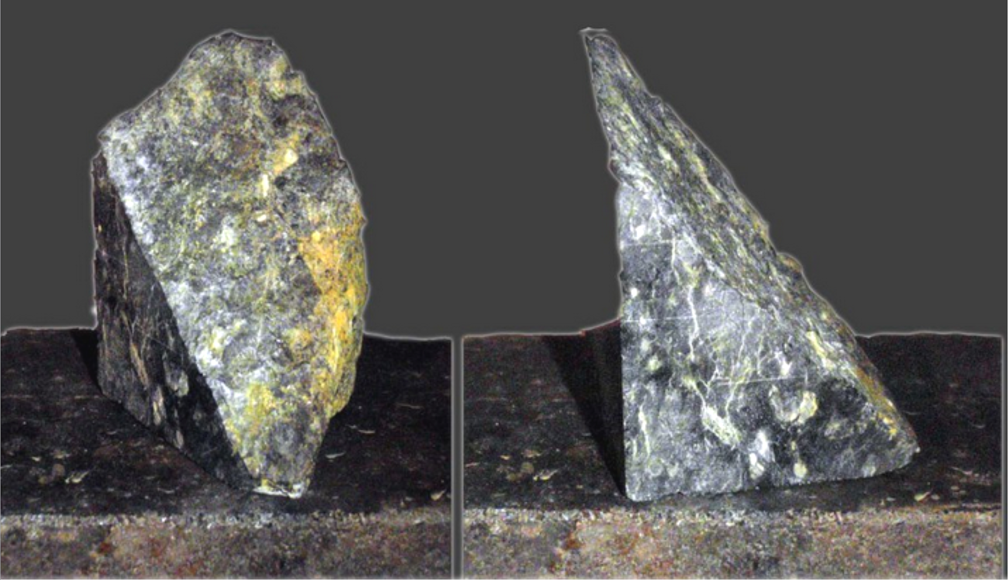 Grom drillings deep within the Mid-Atlantic  Ridge, two pieces of a rock -- one split and one cut and polished to reveal it's composition. Photographed on a dark surface a dark surface against a gray background.