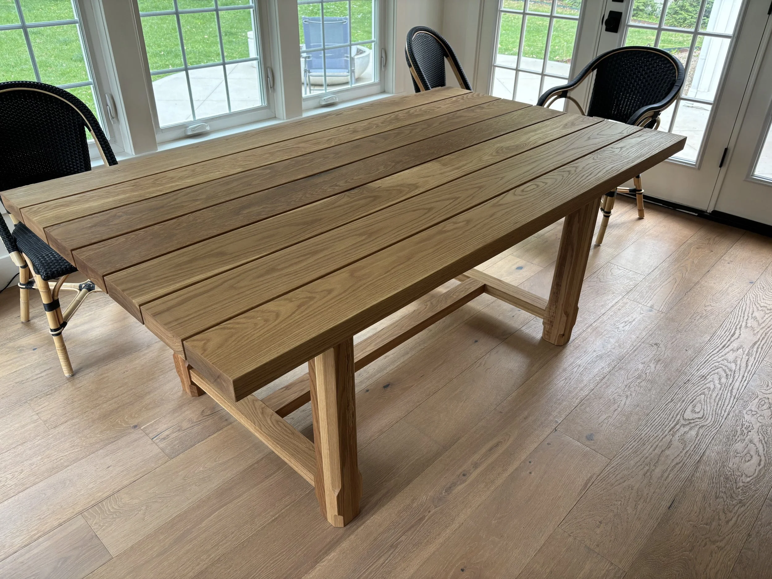 Handcrafted wood outdoor dining table with black chairs by JK Table Co.