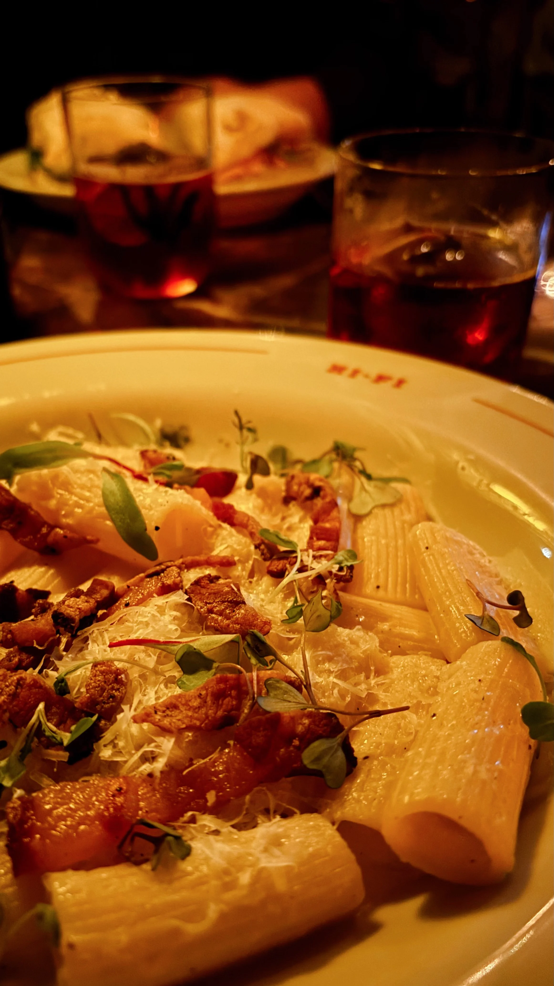 Mesa en restaurante, cena con pasta carbonara y cocteles