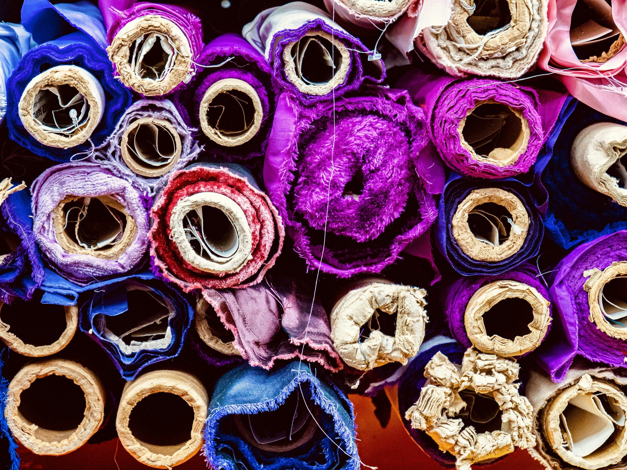Deadstock fabric rolls viewed from the ends of the stacked blue and purple tubes