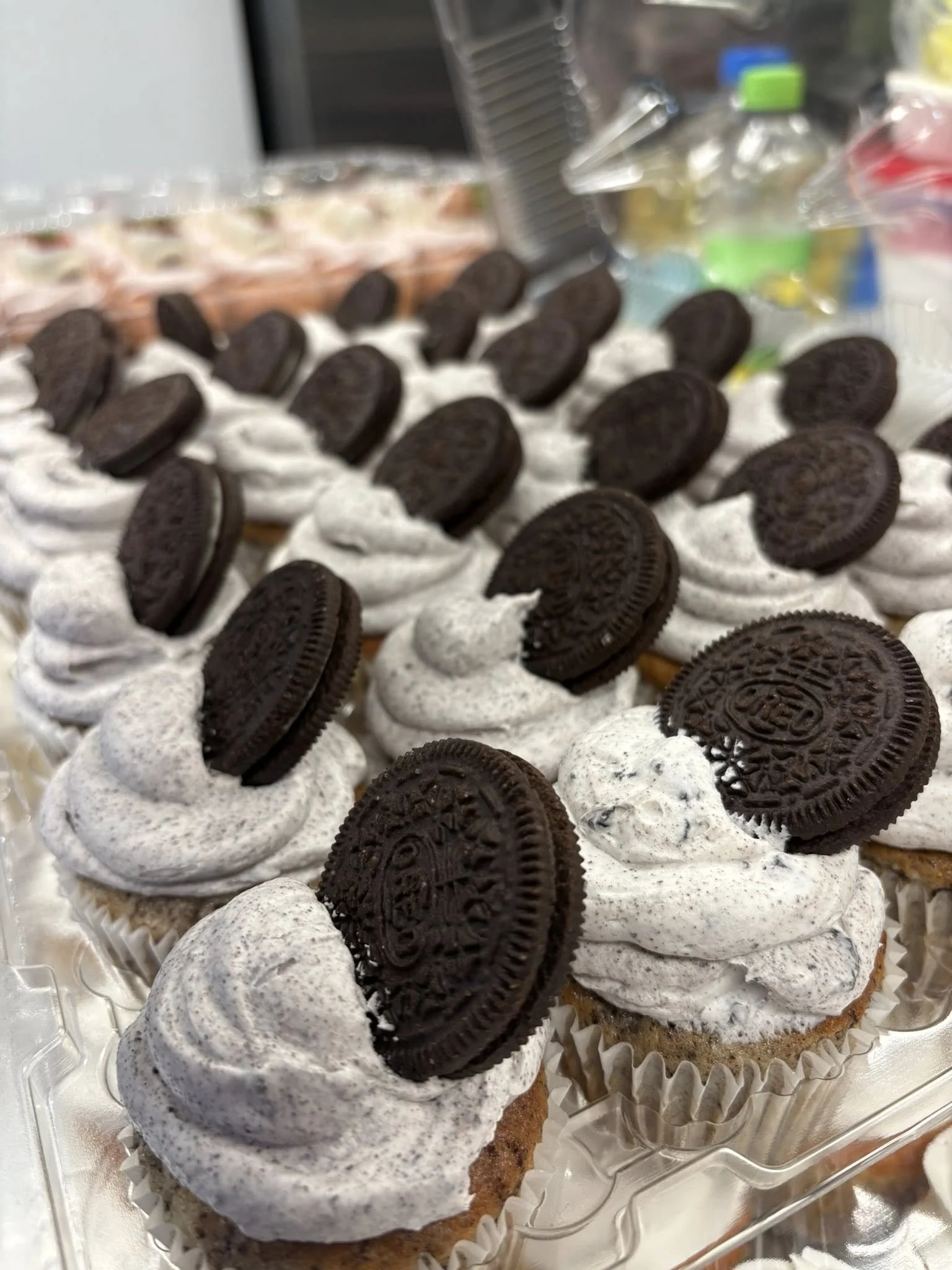 A tray of Oreo topped cupcakes with white frosting.