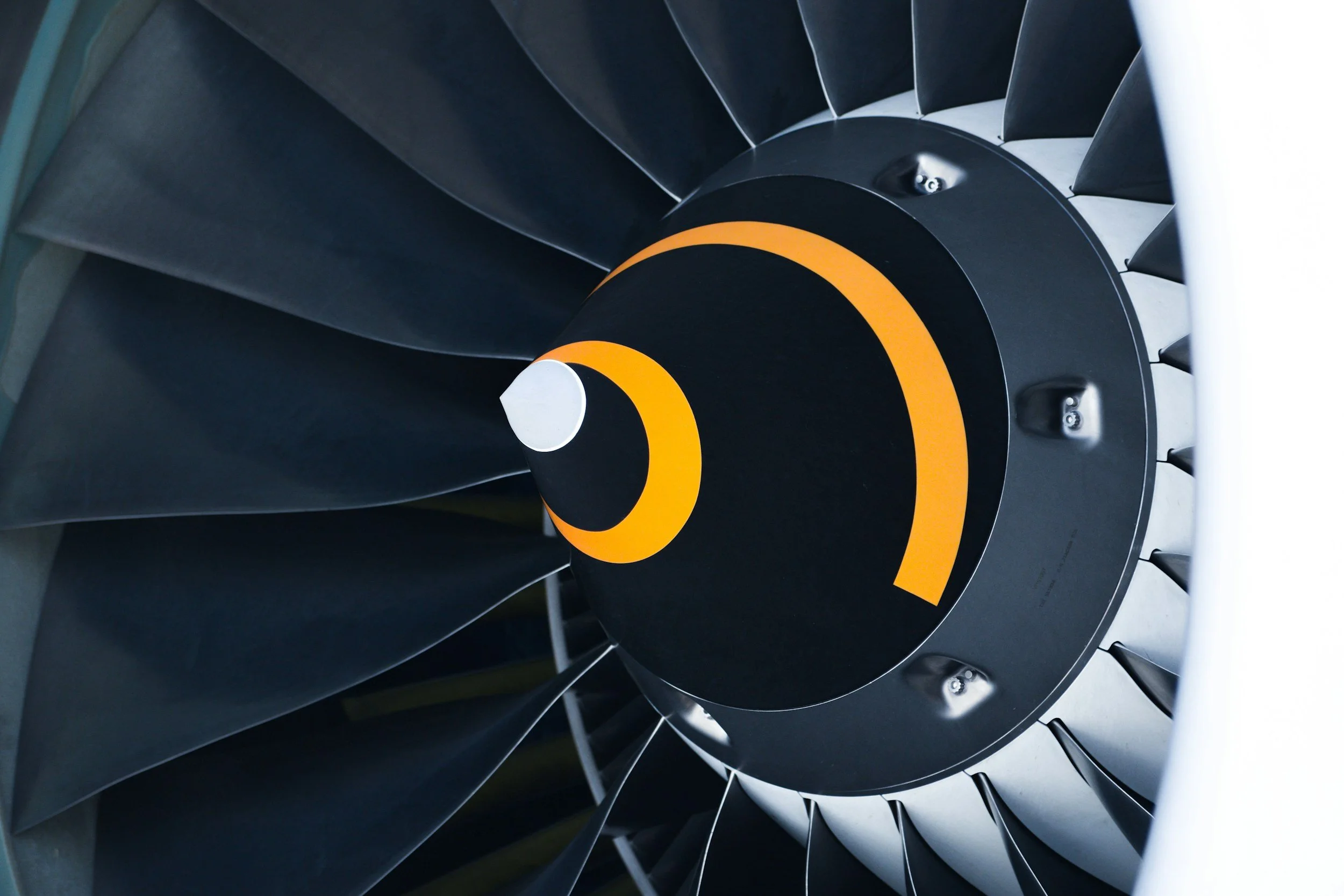 Close-up of a jet engine's fan blades with yellow and black spiral markings at the center.