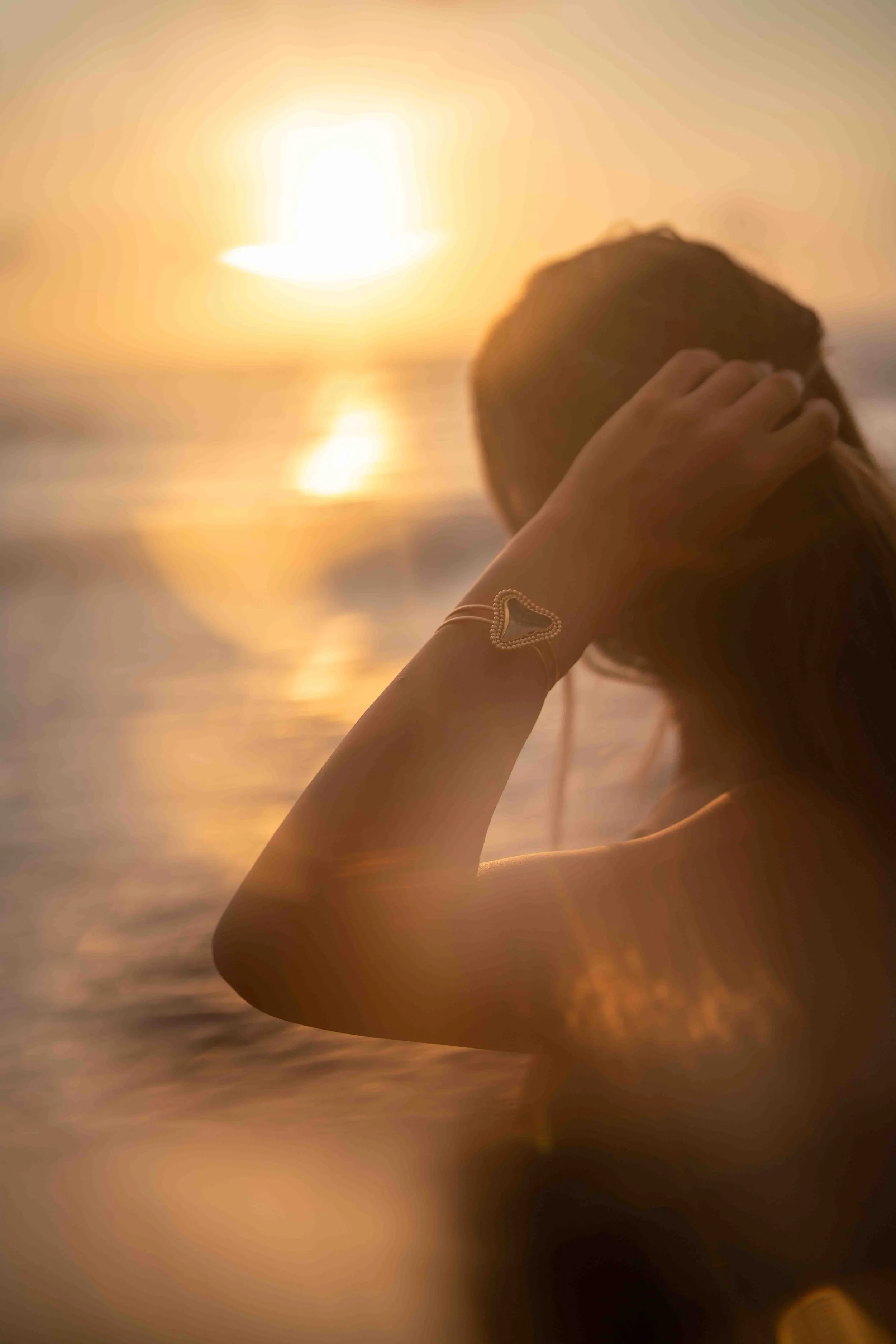 Woman wearing a Tooth & Tide bracelet at sunset by the ocean
