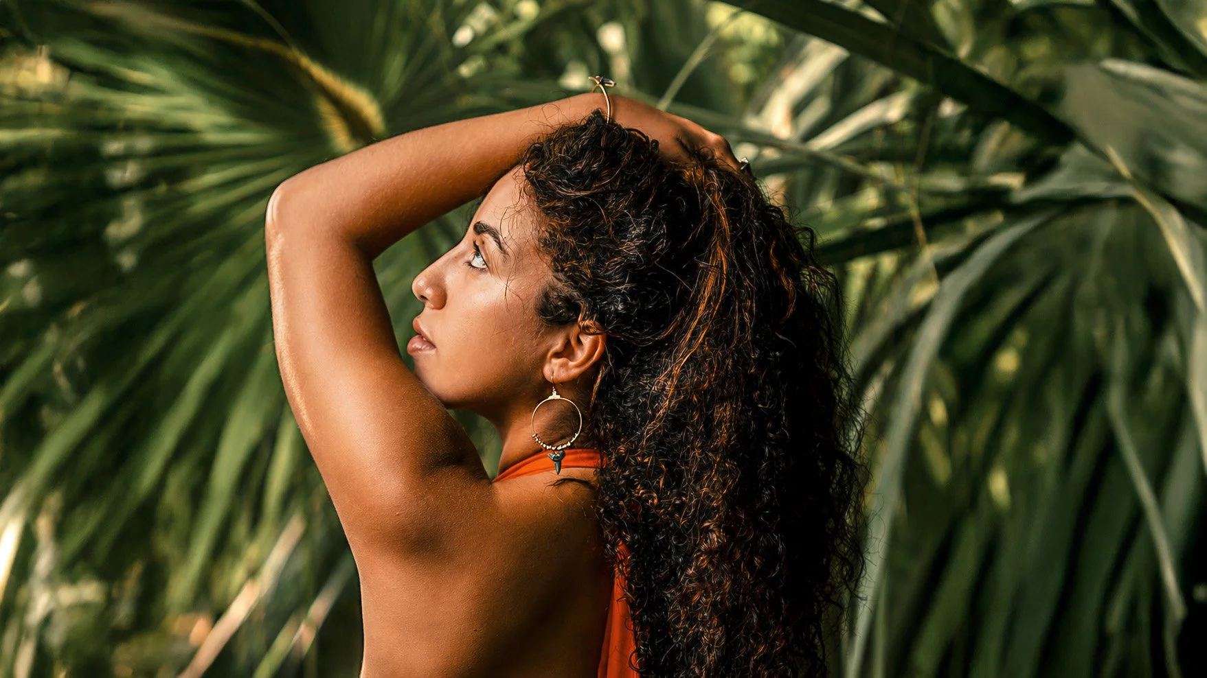 Woman wearing ocean-inspired jewelry surrounded by tropical palms