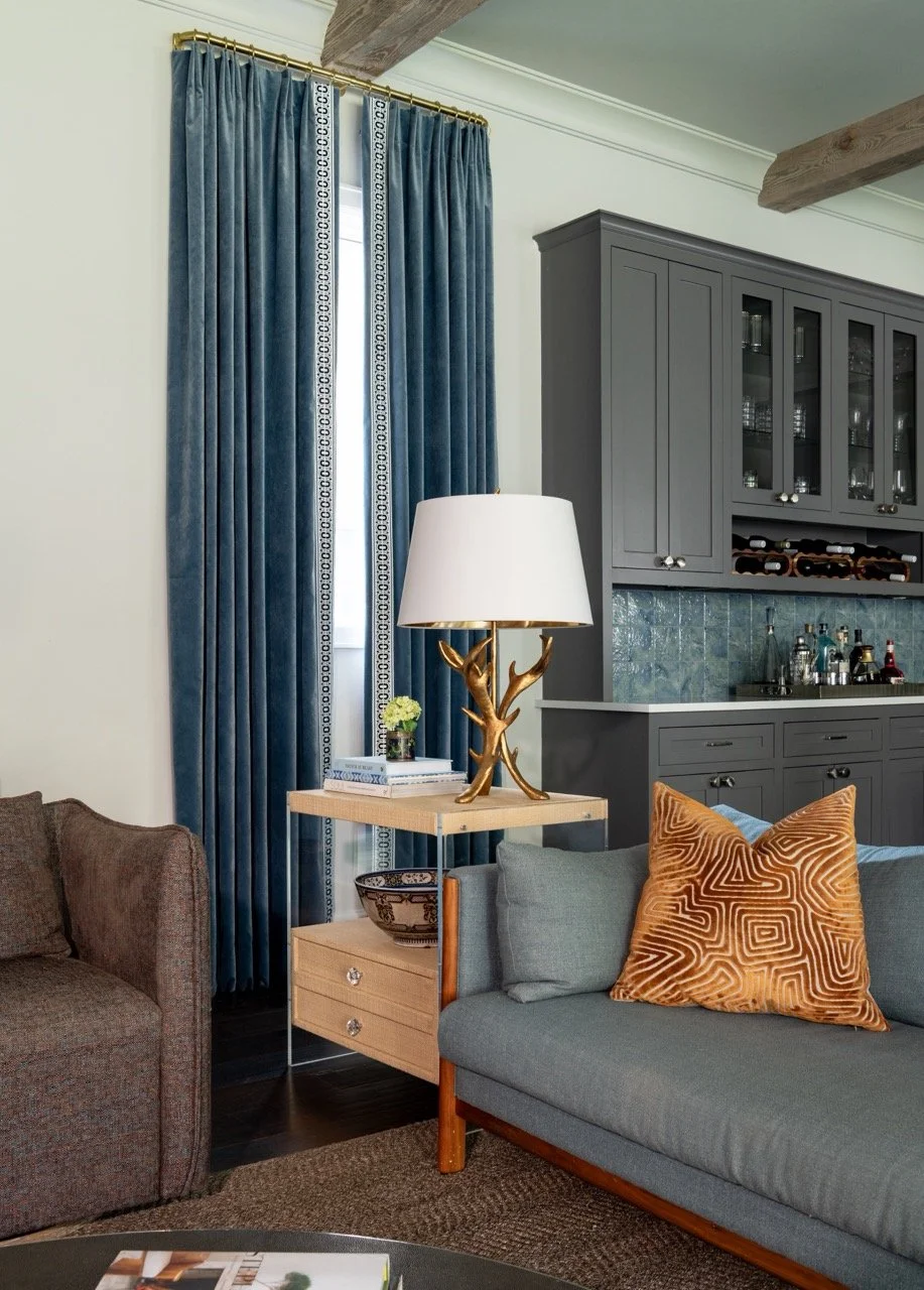Blue sofa styled with a patterned accent pillow in a layered, designer-curated living room