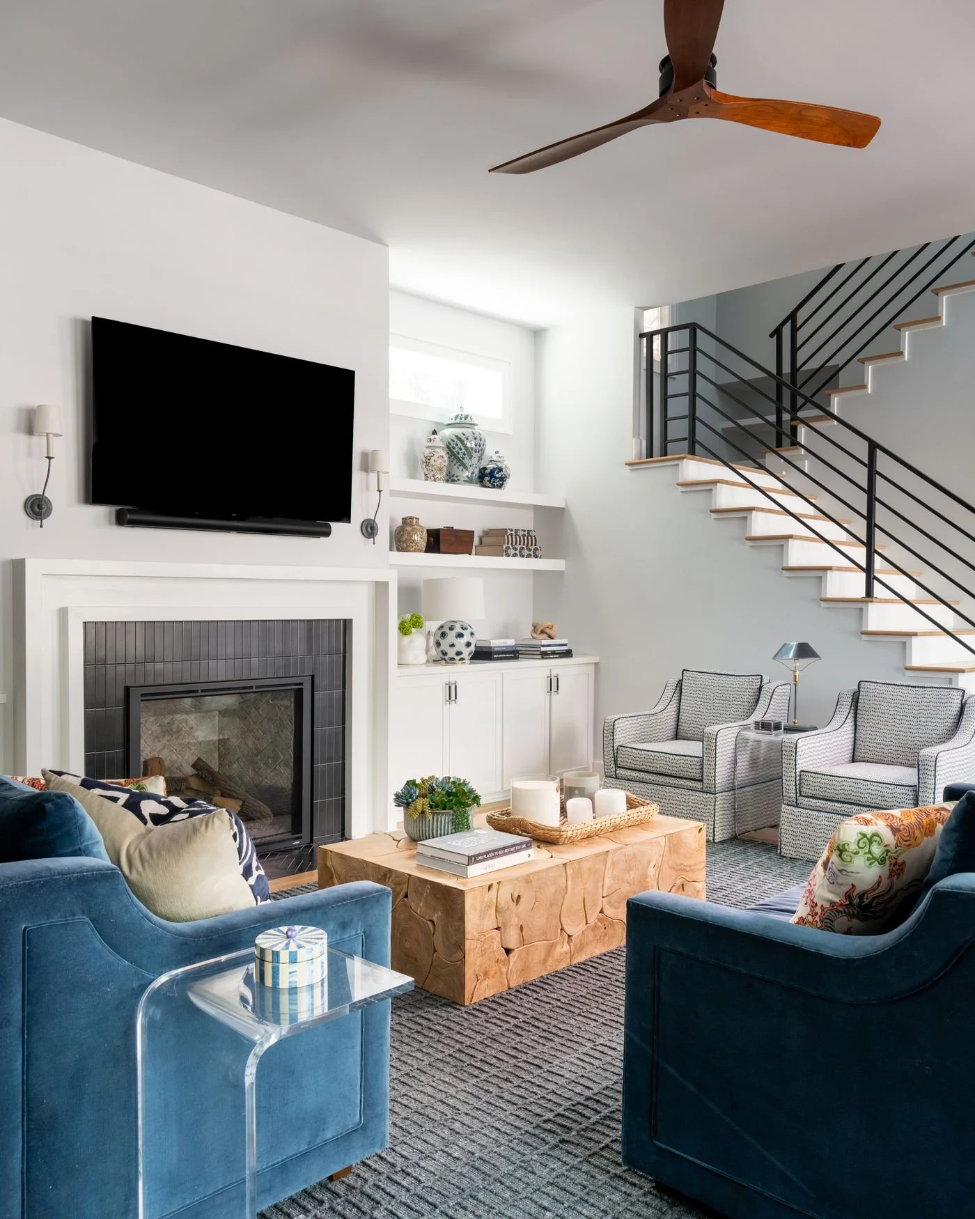 White living room with blue velvet chairs and a burl coffee table