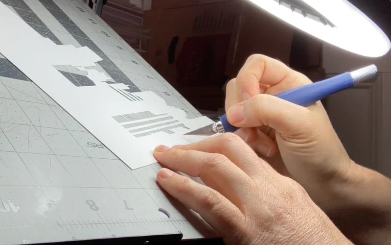 A close up of Evelyn's hands as she cuts paper with a craft knife