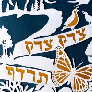 tzedek tzedek tirdof papercut close up of gold accent on the text, butterfly, and bird