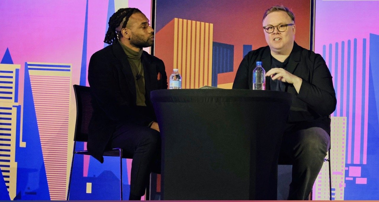 Keenan Medlock interviewing a guest onstage during a live event.