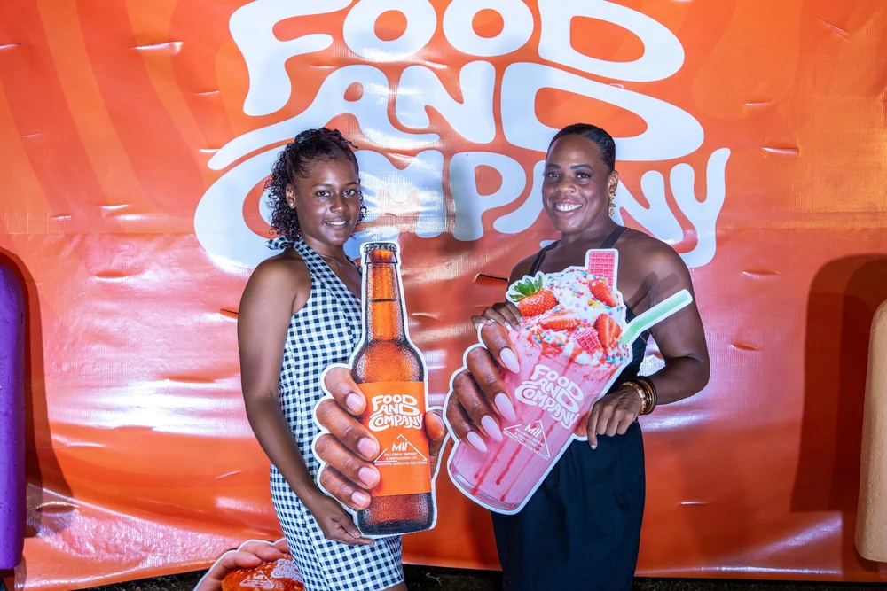 Two guests posing with props at the Food and Company photo wall
