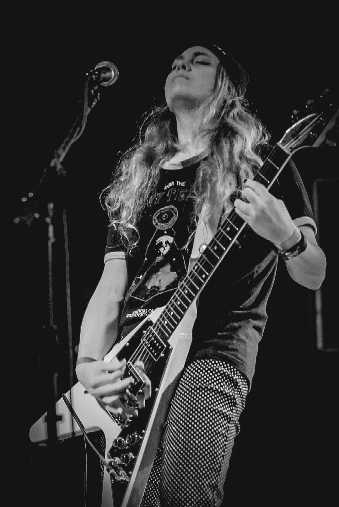A woman playing an electric guitar on stage, black and white photo