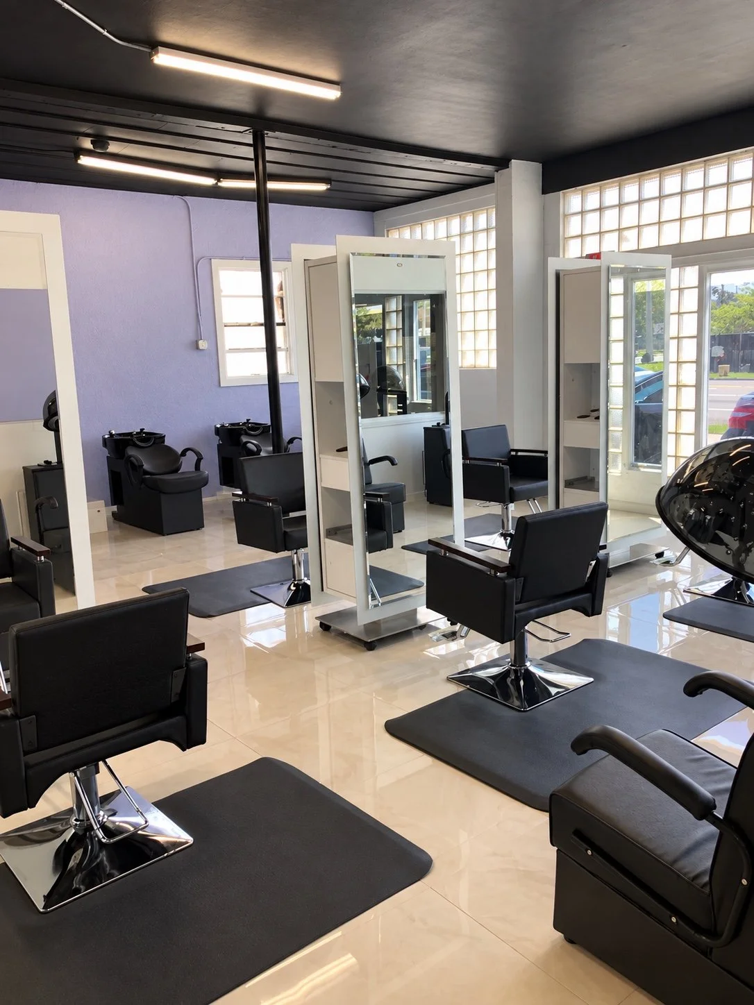 Salon styling stations with full-length mirrors, integrated shelving, and black salon chairs.