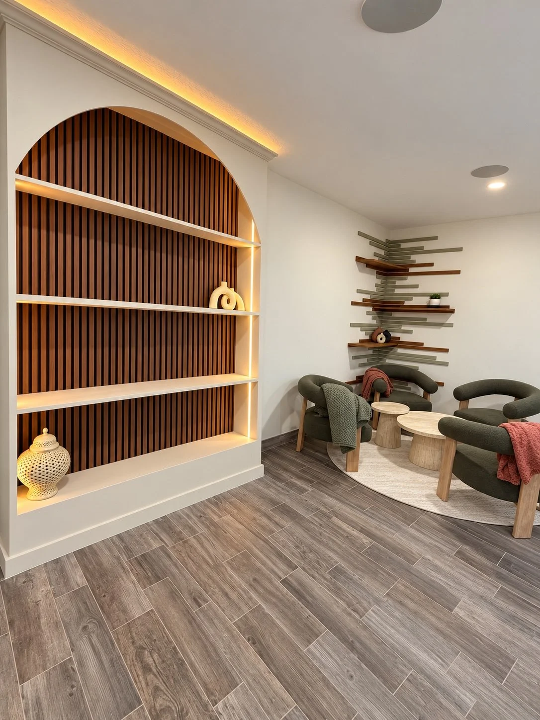 Illuminated arched built-in shelving with a wood slat back.