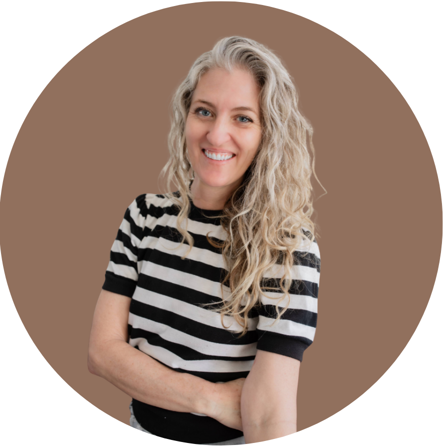 A smiling woman with long curly blonde hair, wearing a black and white striped shirt, standing against a solid brown background.