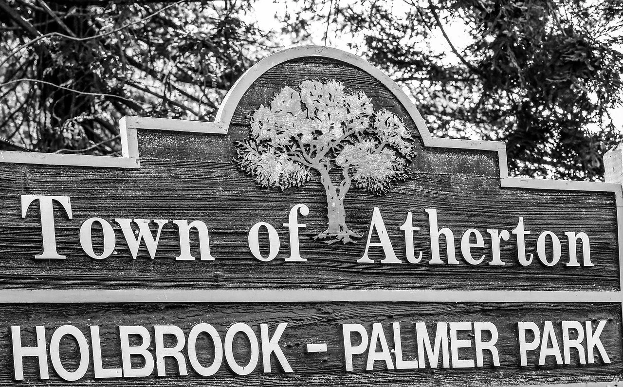 Wooden town sign for Atherton with a tree illustration, indicating Holbrook-Palmer Park.