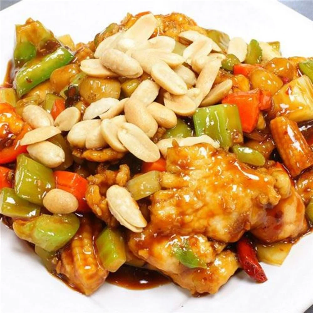 Dish with battered fried chicken topped with a sweet orange sauce, accompanied by stir-fried vegetables including bell peppers, carrots, broccoli, and baby corn, garnished with peanuts.